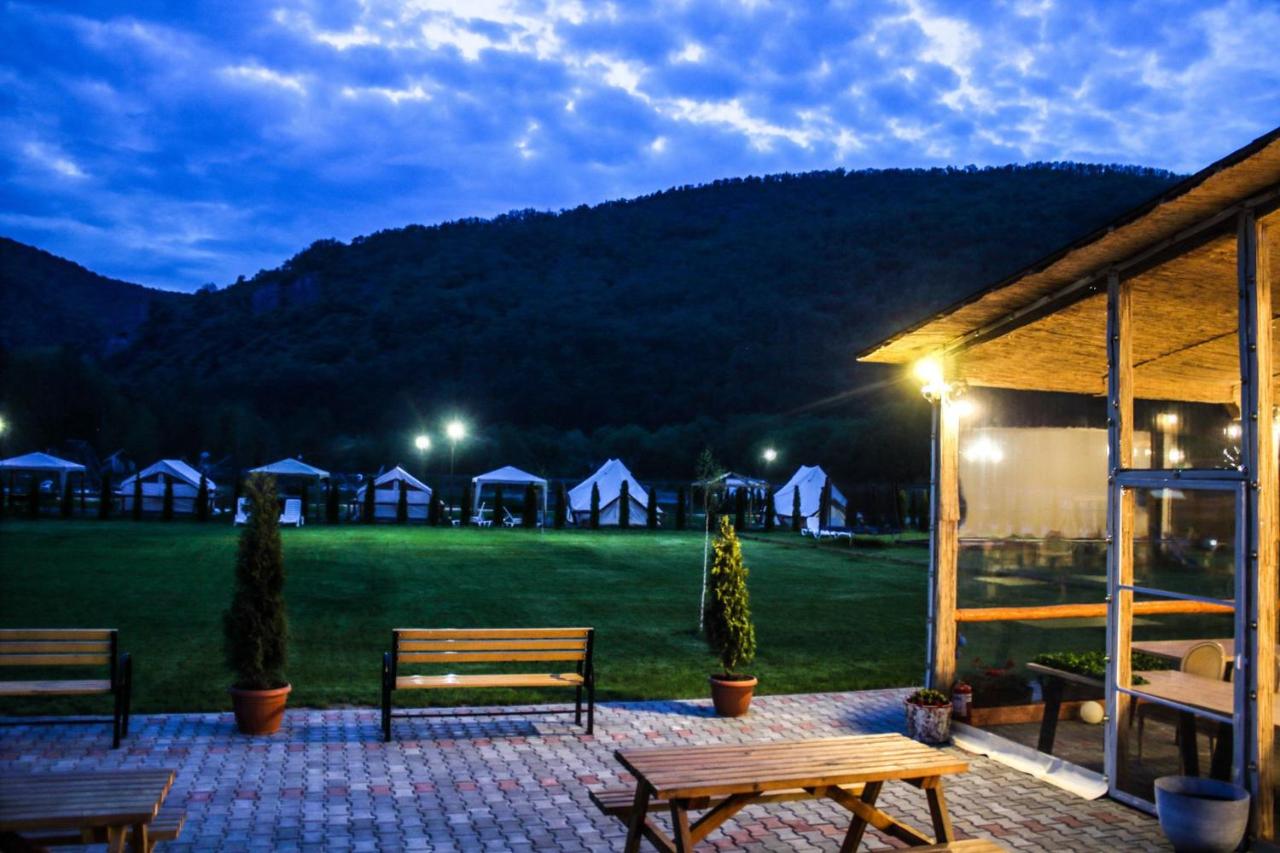 Terasa acoperită a restaurantului seara, cu corturile de glamping luminate în fundal