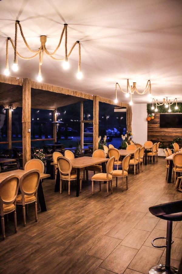 Sala restaurantului cu mese din lemn, scaune tapițate și lumini calde în candelabre