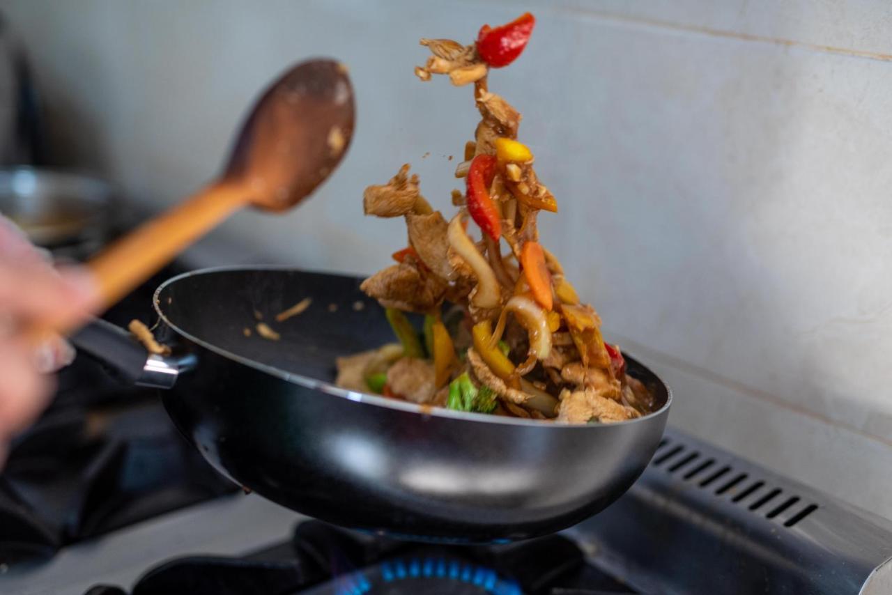 Bucătar flambând legume într-o tigaie, în bucătăria restaurantului
