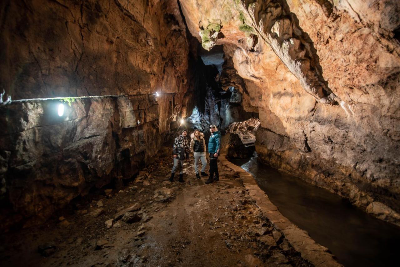 Vizitatori cu lanterne explorând o galerie de peșteră din defileu