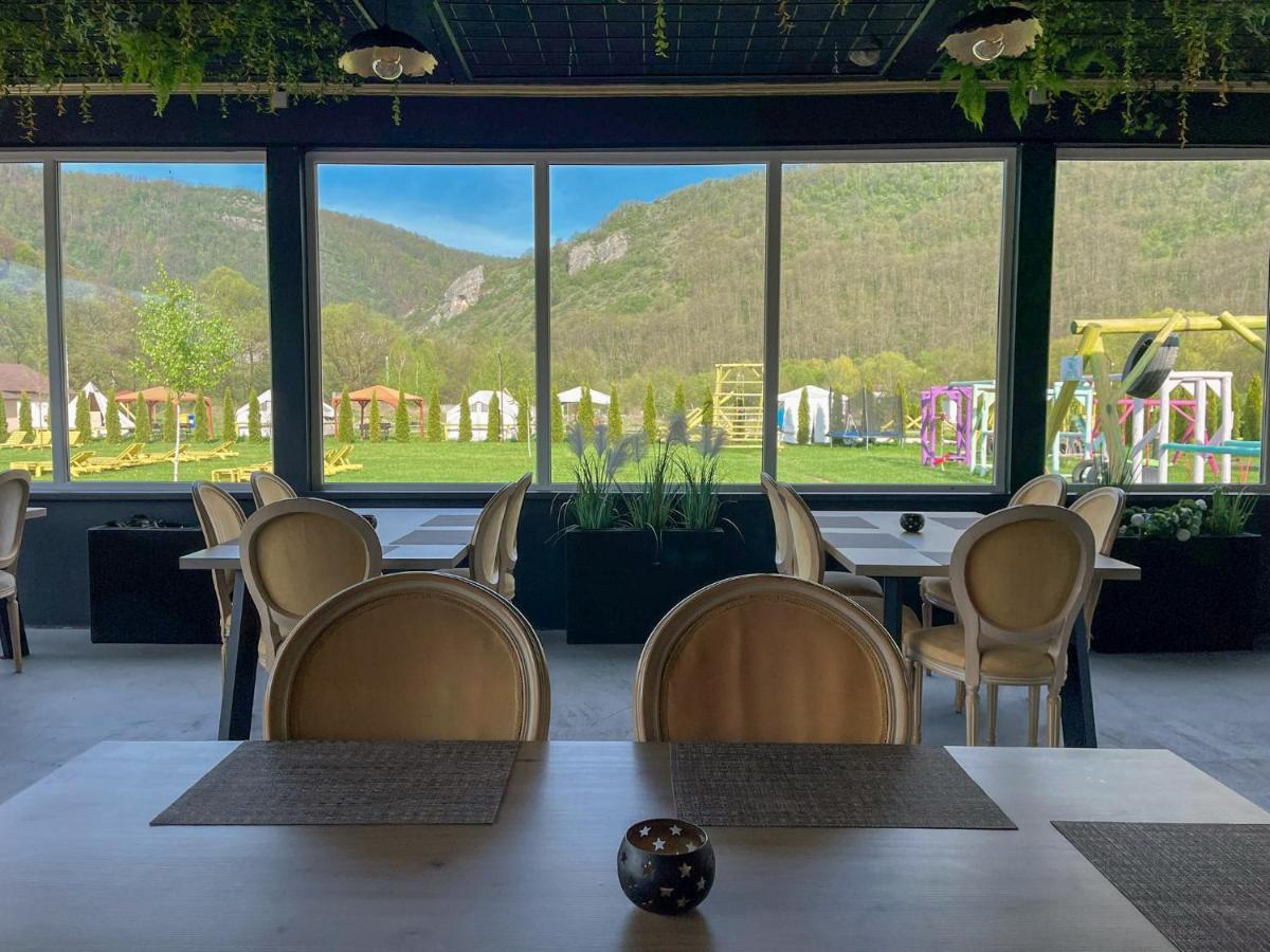 Sala de mese cu ferestre panoramice spre poiana resortului și dealurile din jur