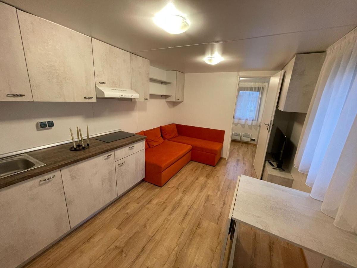 Livingul apartamentului, cu bucătărie complet utilată și canapea portocalie