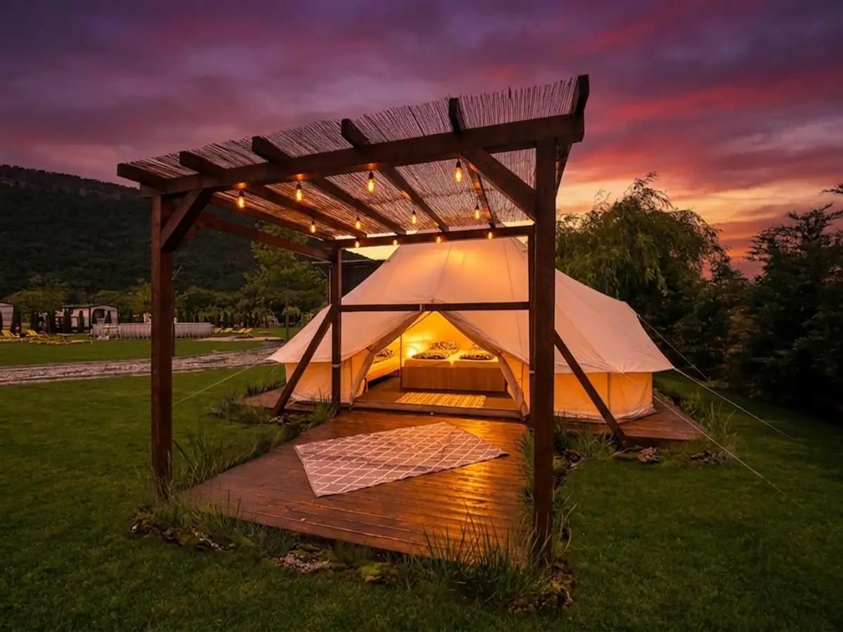 Cort de glamping cu pergolă din lemn, fotografiat la apus