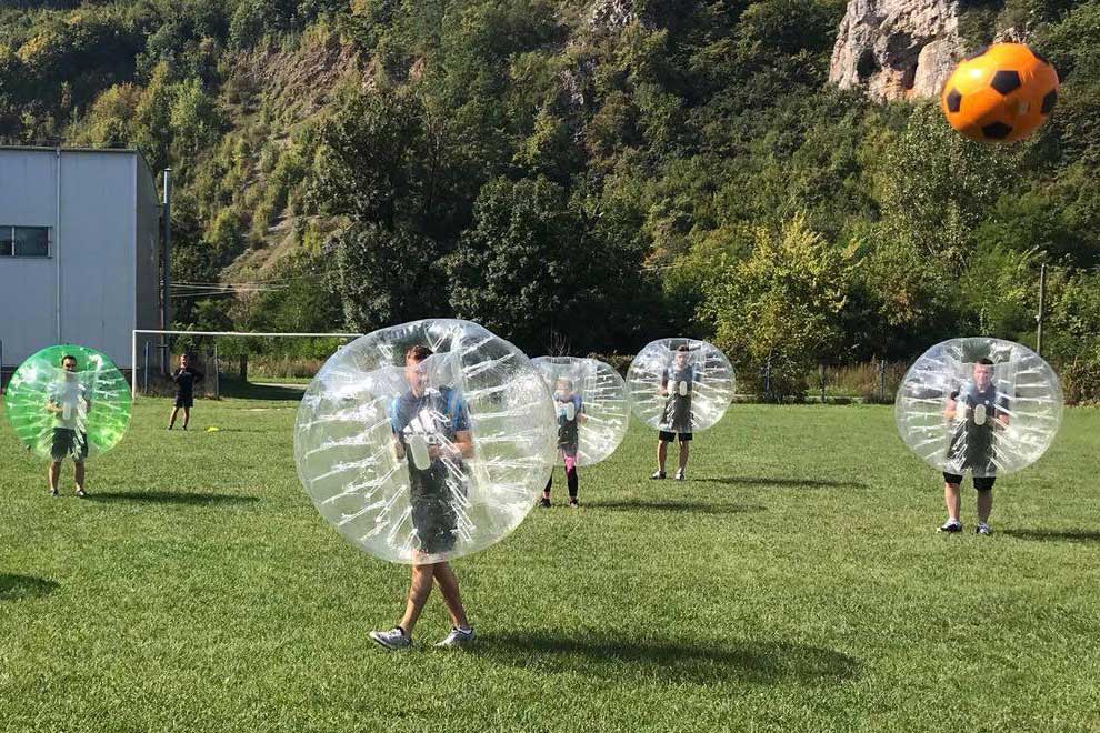Joc de bubble soccer cu participanți în bule gonflabile transparente