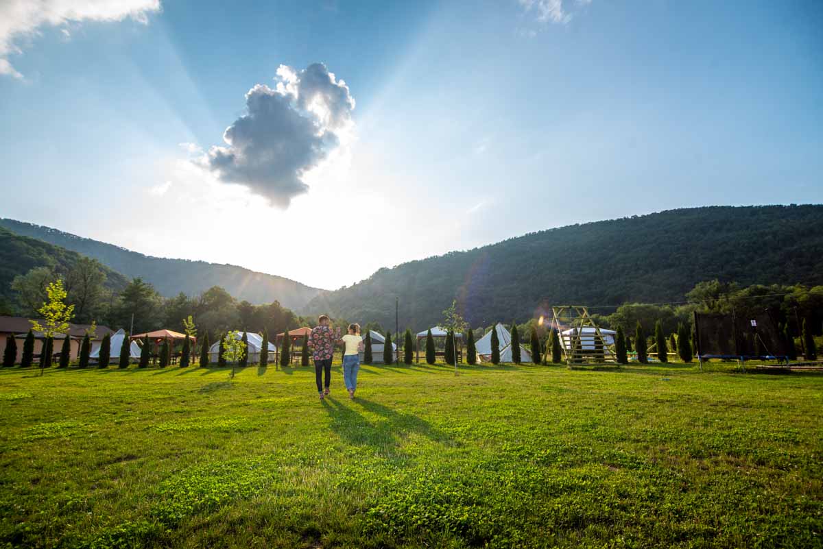 Corturi și rulote pe locul de campare, înconjurate de verdeață