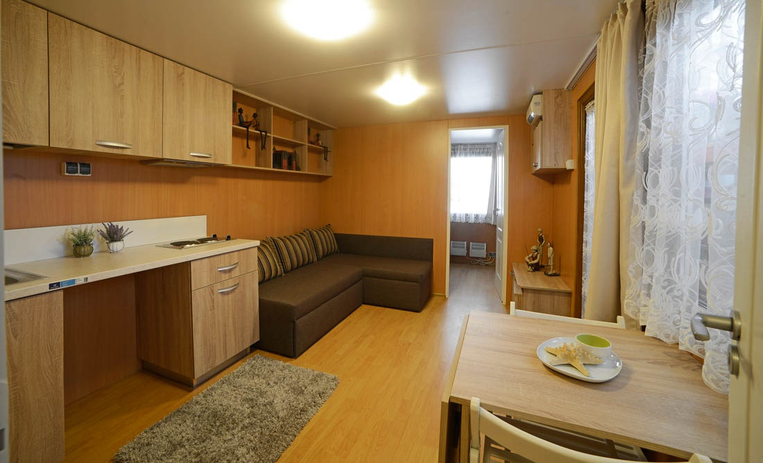 Interiorul unei căsuțe mobile cu bucătărie și living luminos