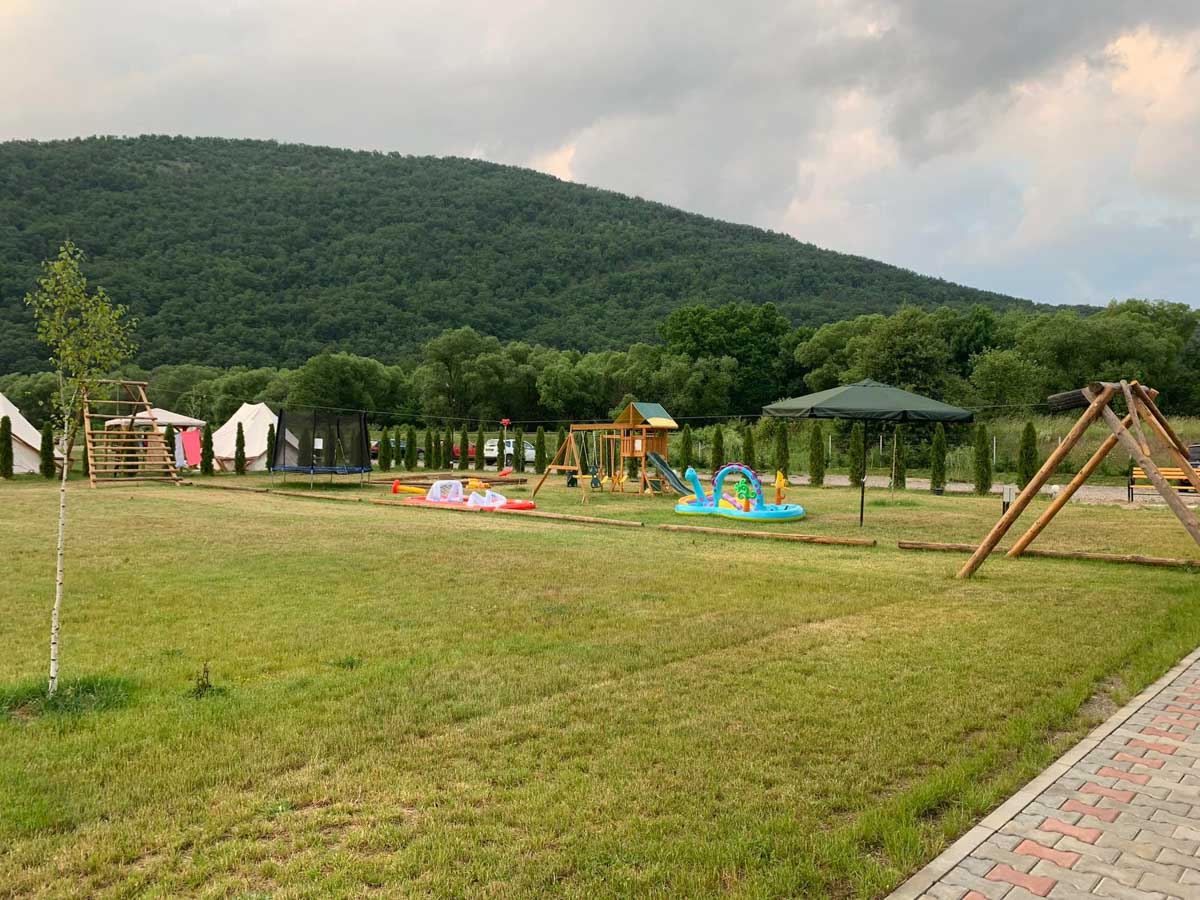 Pajiște cu piscina și căsuțele resortului într-o zi de vară