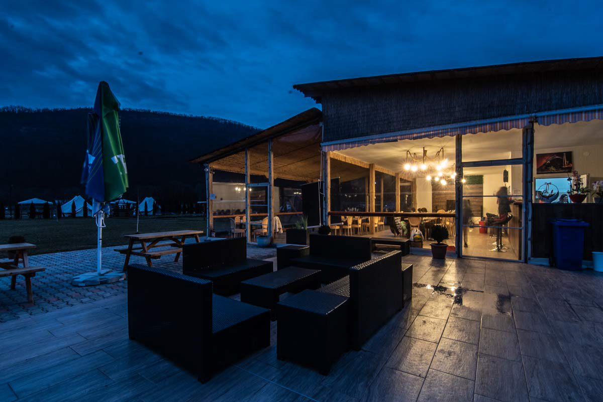 Terasă lounge acoperită la amurg, cu umbrele și fotolii