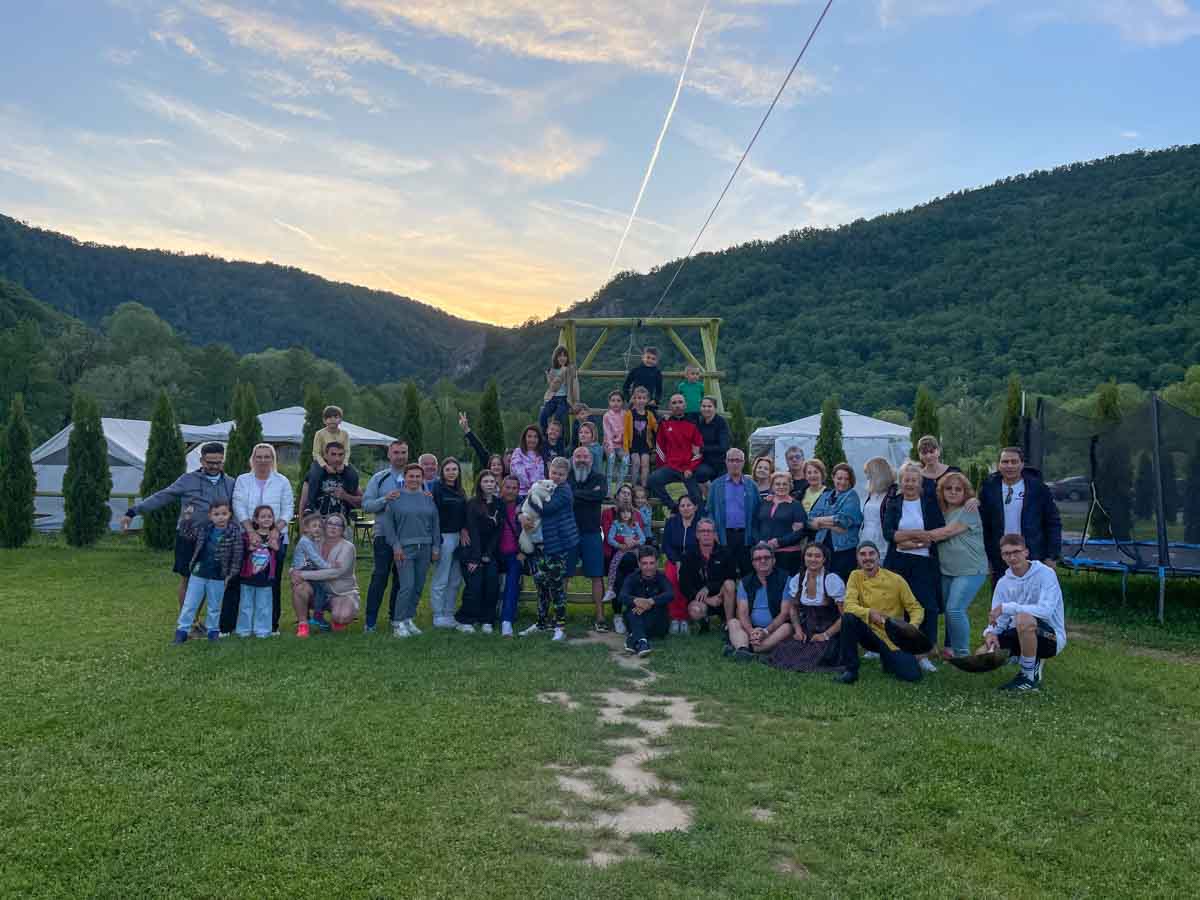 Grup numeros la team building, fotografiat pe pajiștea resortului cu defileul în spate