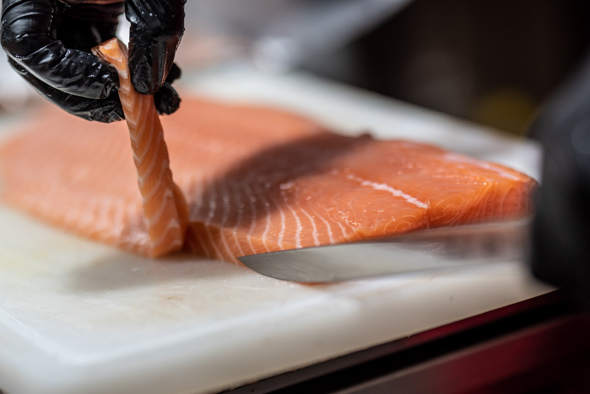 Bucătar tăind file de somon proaspăt pentru sushi